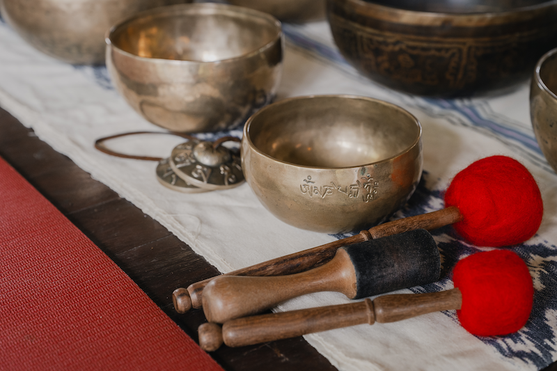 Brass Tibetan singing bowls and mallets laid out on a woven cloth