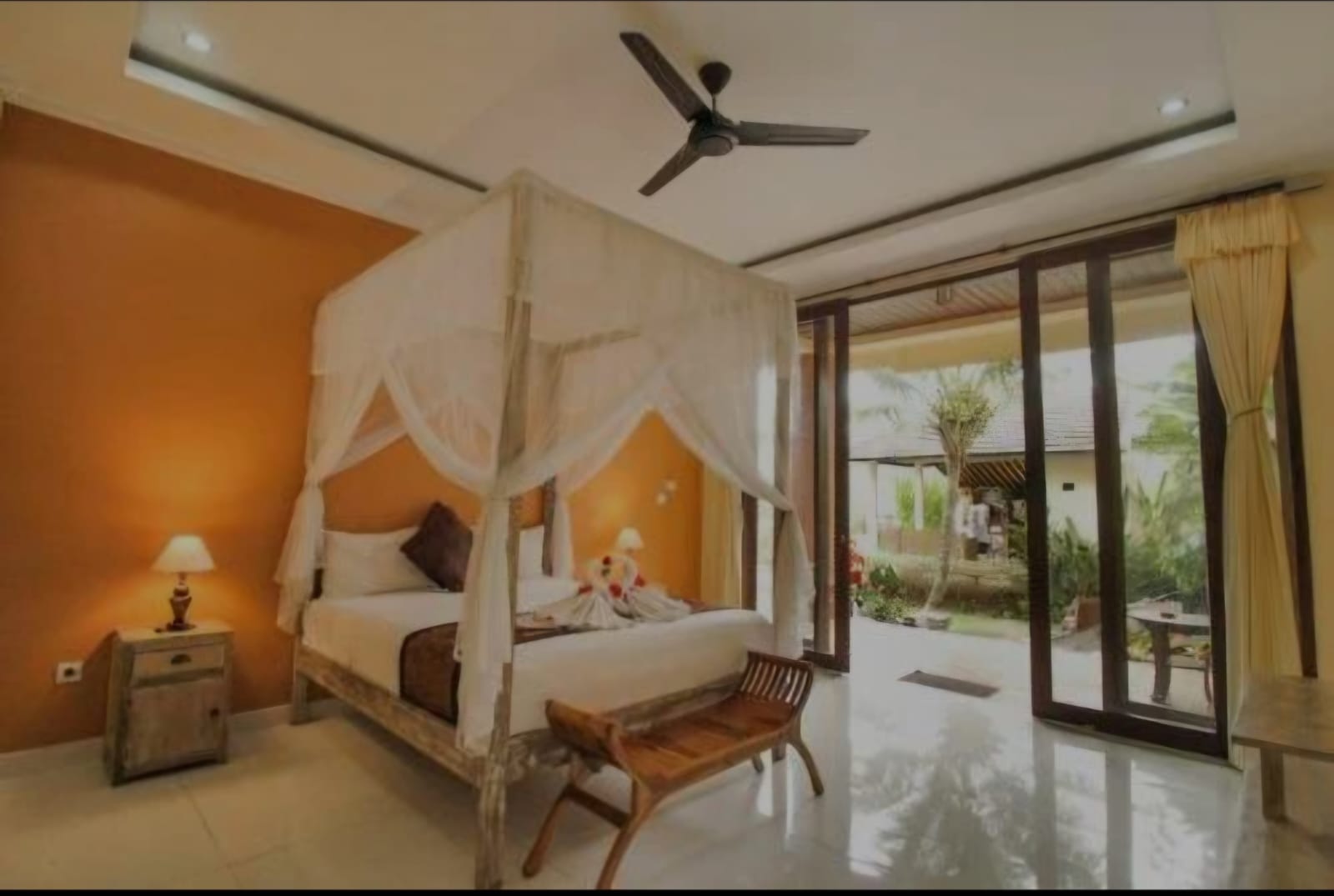 A canopied bed in a guest room opening onto the garden