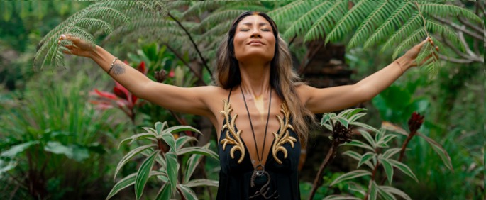 Woman in a Bali jungle opening her arms to the ferns