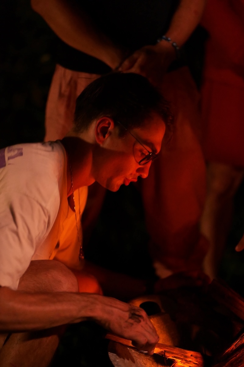 A man tending the fire by candlelight