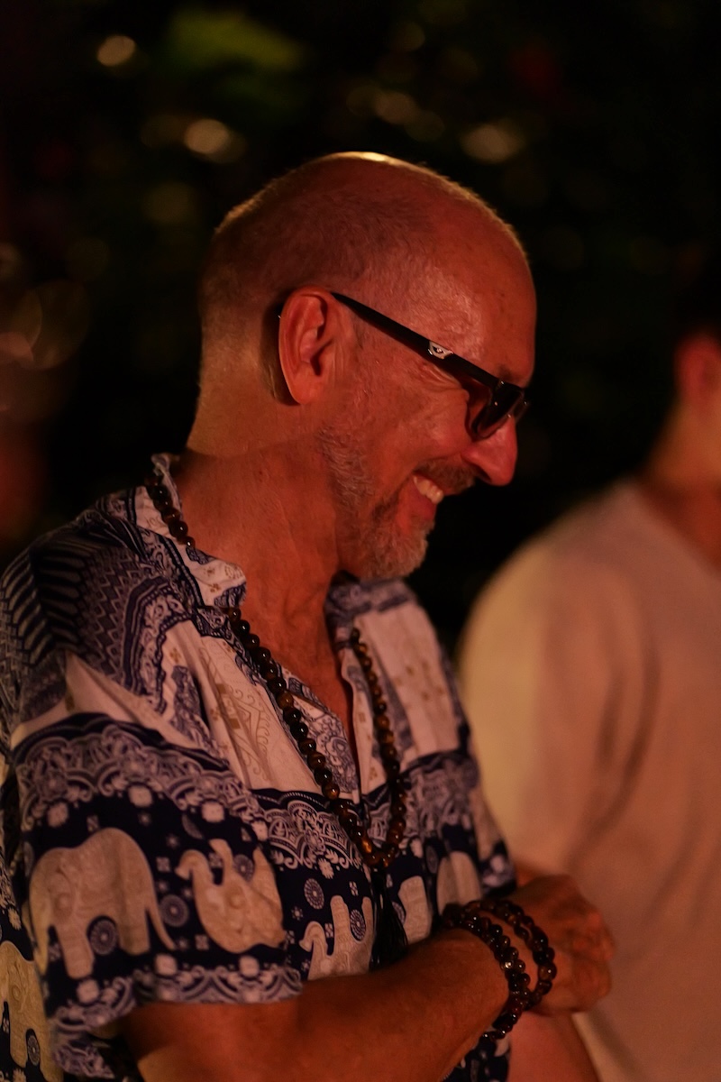 A man smiling in firelight at the closing ceremony