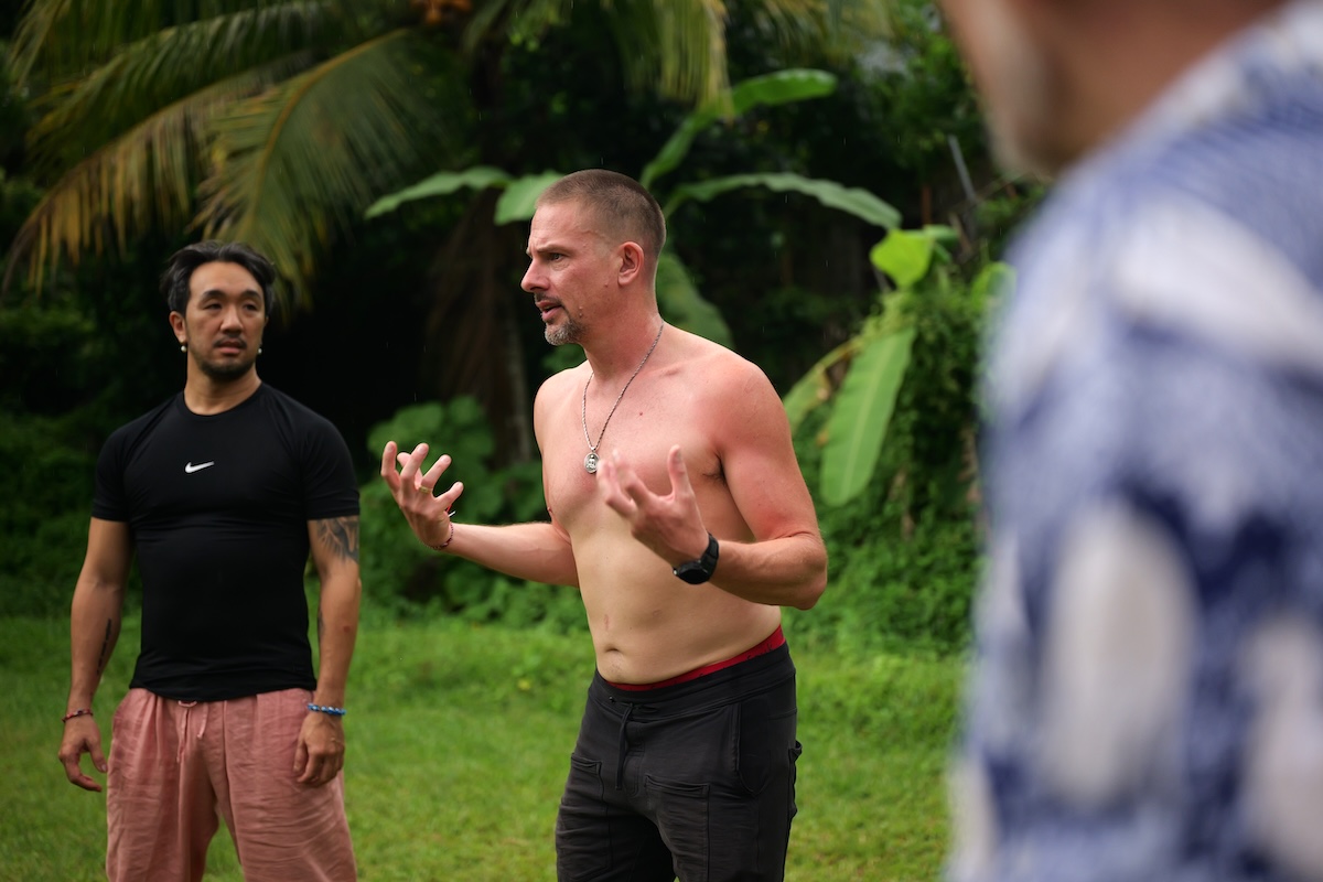 A man speaking with hands raised in a circle of brothers